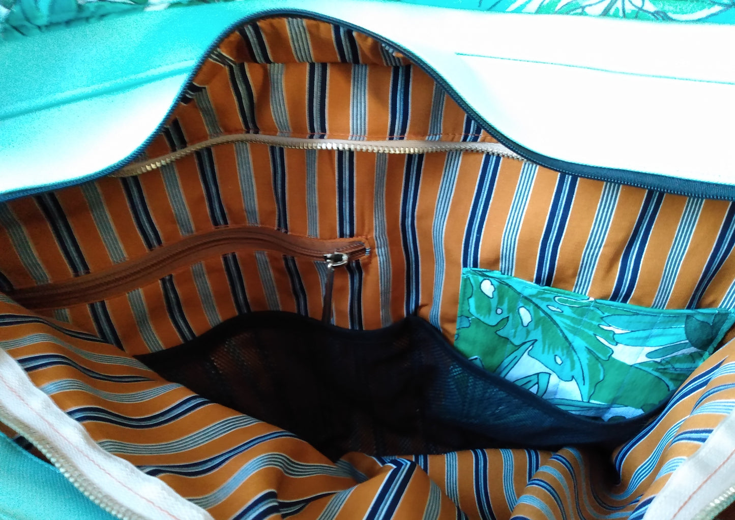 Vue de l'intérieur de la poche zippée à l'intérieur du sac cabas Amarante. Dans cette poche sont présents une seconde poche zippée, une poche à stylos (en tissu feuille verte) et une poche en filet.