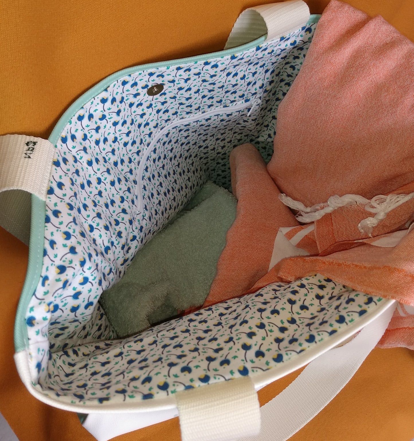 Intérieur du sac Tara. il possède un fermir magnétique et une poche zippée. La doublure est en coton blanc imprimé tulipes bleues.