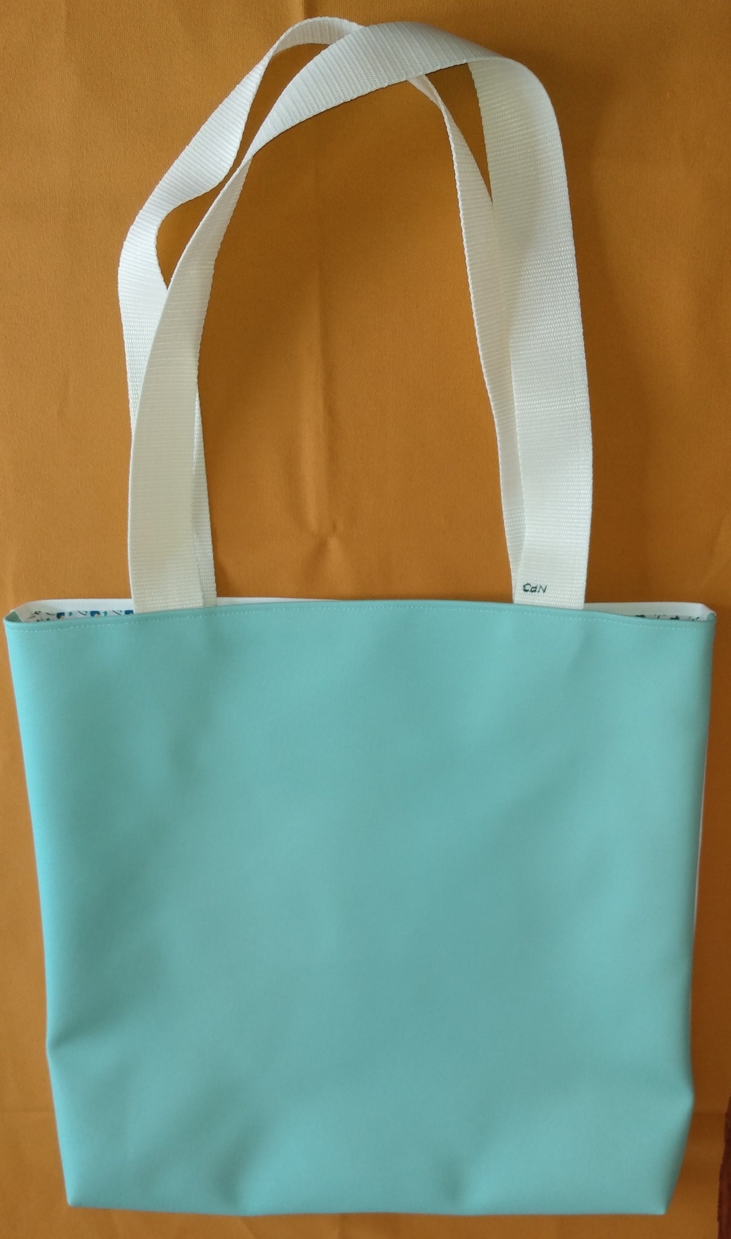 Arrière du sac Tara. Il est en simili cuir couleur unie vert d'eau. Les anses sont de couleur blanc cassé.
