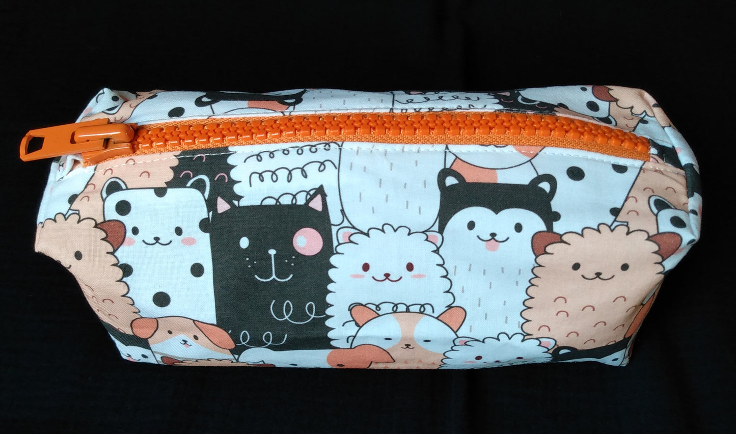 Trousse taille 2. Coton imprimé chiens saumon blanc et noir. La fermeture éclair est en plastique et métal orange.