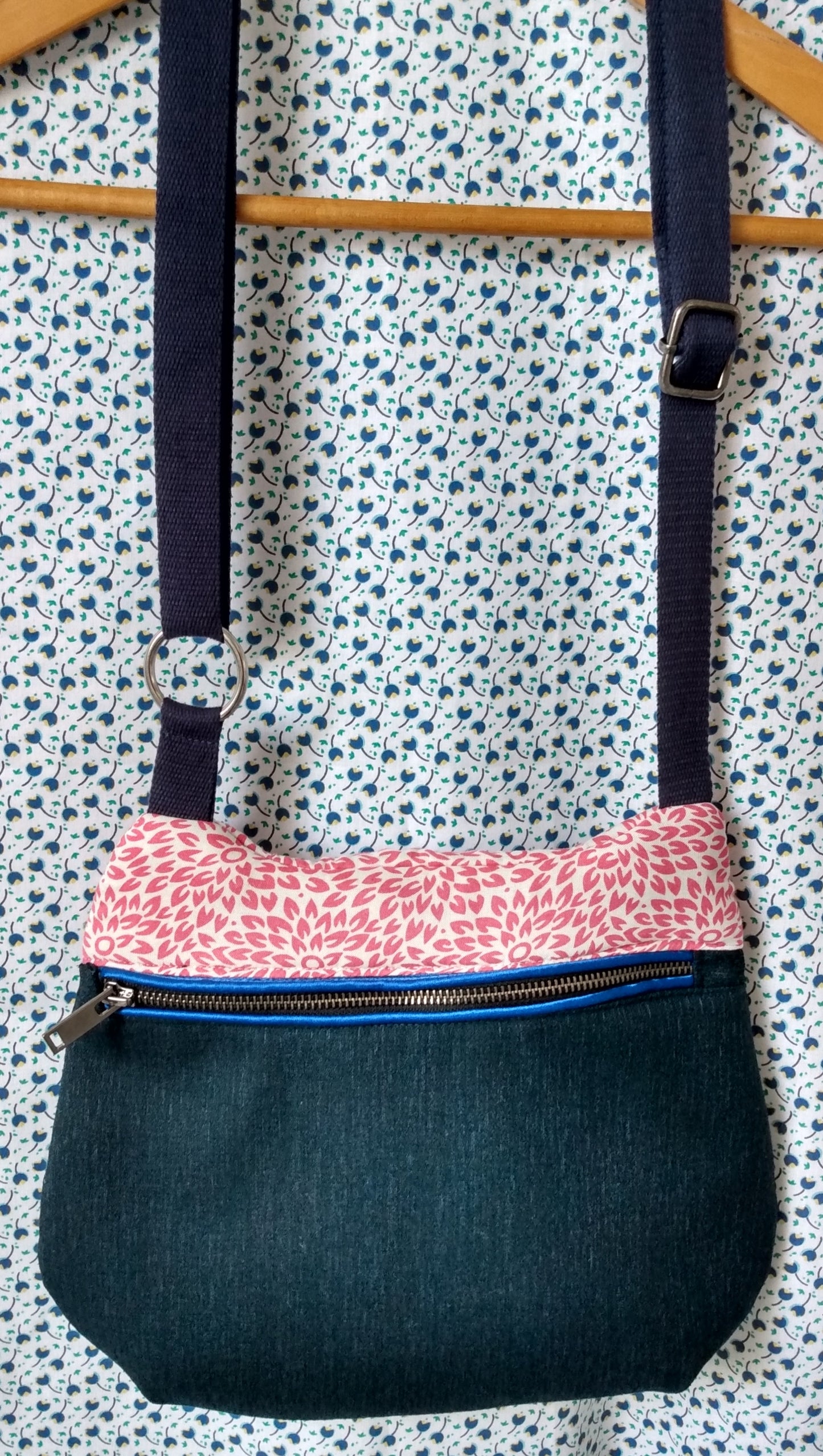 avant du sac pivoine couleur marine et rose. Le bas du sac est bleu marine, le haut du sac en coton beige à fleurs roses. Le sac se ferme avec une fermeture éclair métallisée noire passepoilée. La bandoulière réglable du sac est bleue marine.