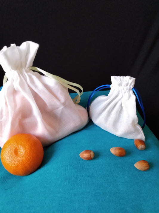 Un sac à vrac blanc de grande taille contenant des clémentines et un sac à vrac plus petit contenant des noisettes sont fermés et entourés de clémentines et de noisettes