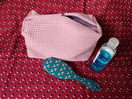 Trousse de toilette en coton nid d'abeille mauve. Se ferme avec un zip. Doublure intérieure en coton uni mauve.