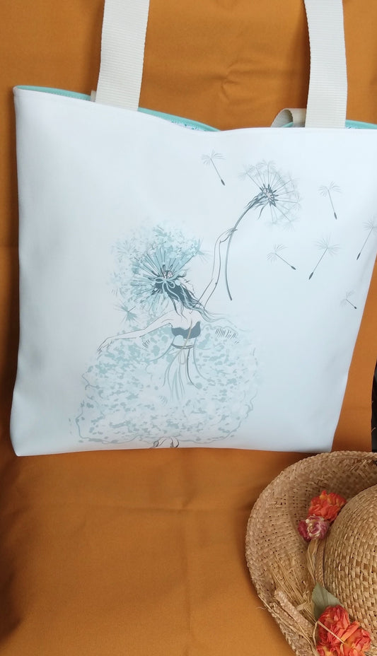 Face avant du sac Tara. Elle est en simili cuir blanc cassé, au centre est dessinée une danseuse tenant un pissenlit dans sa main. Les anses sont aussi couleur blanc cassé.