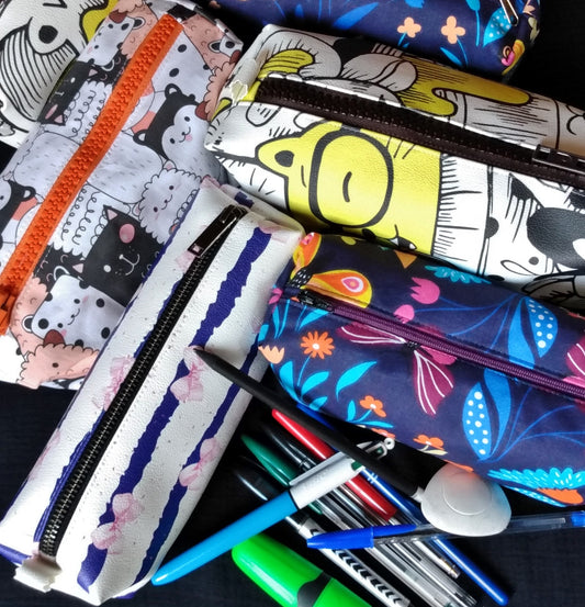 plusieurs trousses avec différents motifs sont visibles ainsi que des stylos.