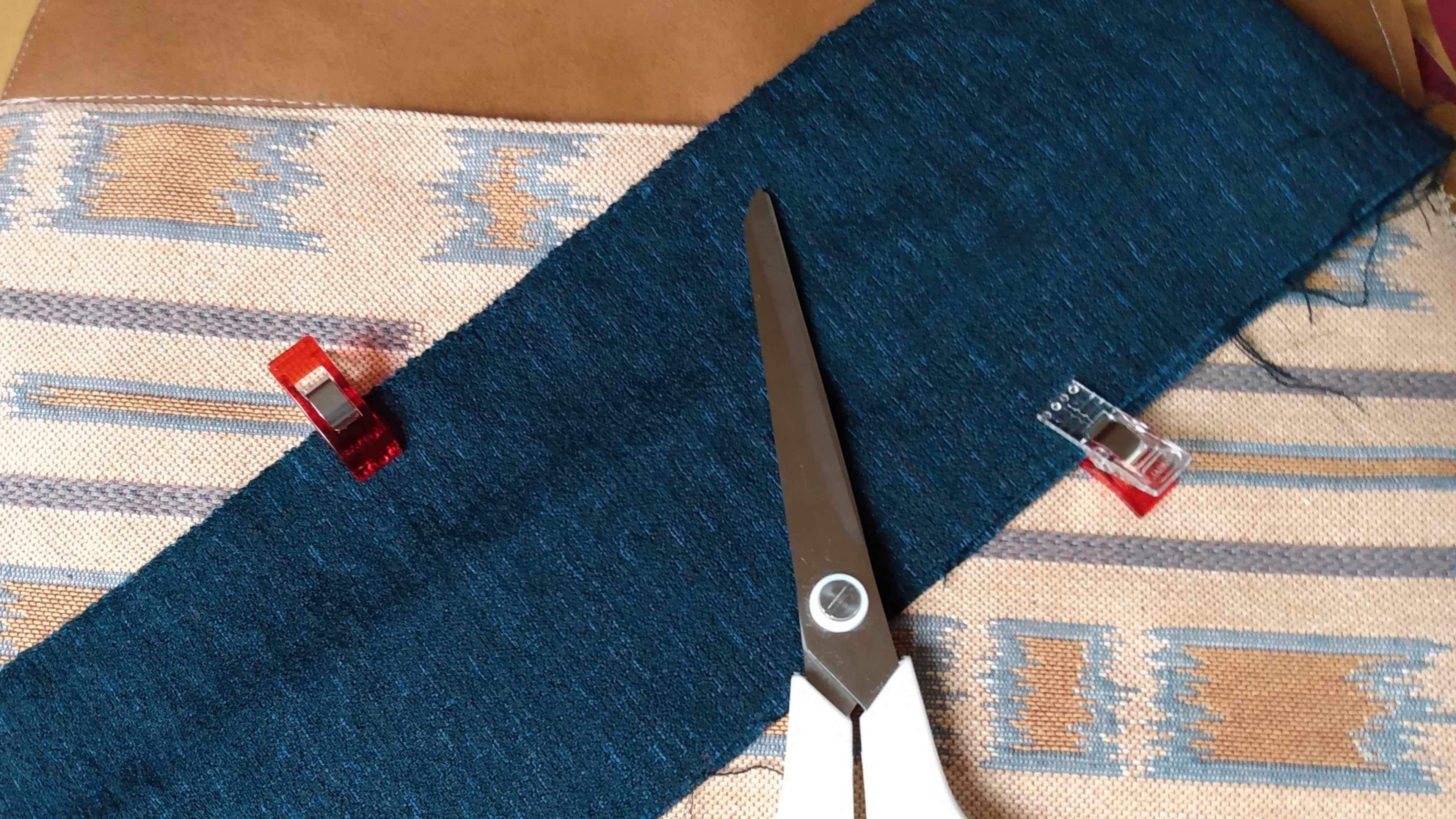 plusieurs tissus posés les uns sur les autres et des ciseaux de couture.