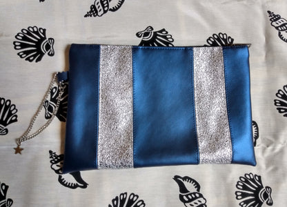 Vue avant pochette Soglad bleu et argent. Des bandes verticales (5) alternes entre bleu métallisé et argent. une chainette permet le port au poignet. Une fermeture éclair ferme la pochette.