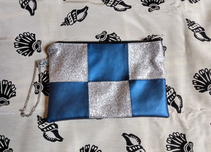 vue avant pochette formidam. Damier bleu et argent. Dragonne sur le côté. Fermeture éclair pour fermer la pochette.