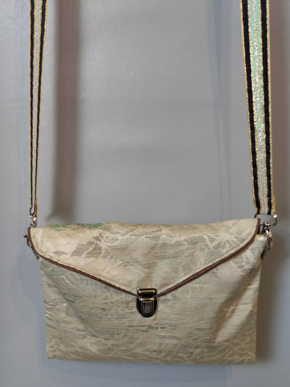 Avant de la pochette Kawa vert clair à motifs montagnes. Pochette se fermant par un rabat et une attache cartable nickelée. Le rabat est passepoilé (marron). Tissu extérieur tons verts à motif montagnes irisés.