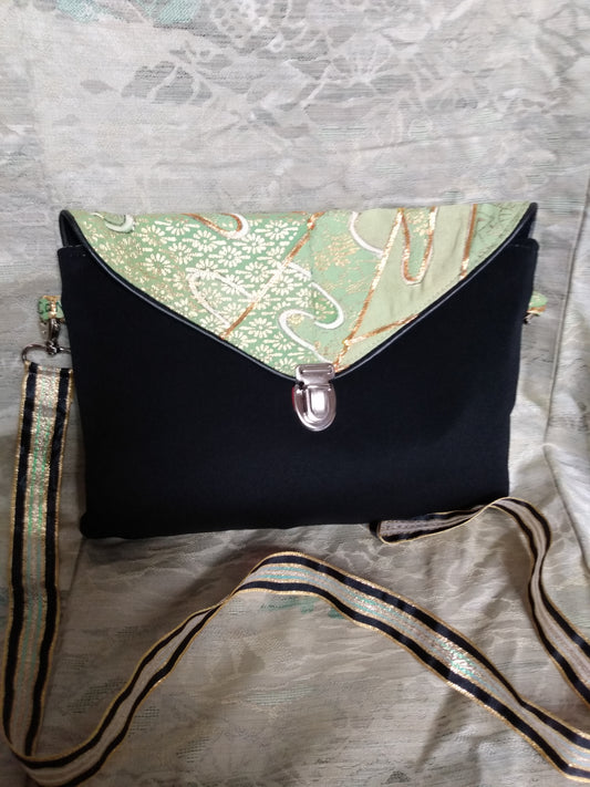 Pochette Kawa vue de devant. Pochette à rabat se fermant avec un fermoir cartable. Anse permet le port en bandoulière ou à l'épaule.