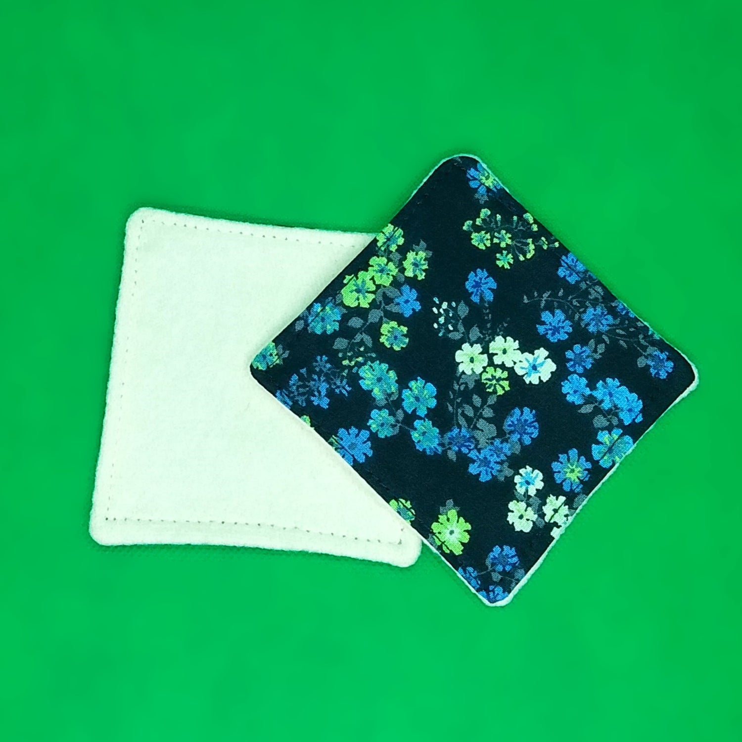 Lingette démaquillante. Une face en molleton de chanvre beige et une face en coton imprimé fleurs vertes et bleues sur fond marine.