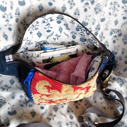 Vue intérieure du sac Mango. Le sac est ouvert via l'ouverture principale qui est une fermeture en métal. Il est rempli d'accessoires. On voit ainsi une poche avec 3 compartiments à cartes et une seconde poche à l'arrière. La doublure intérieure est blanche à fleurs bleues.