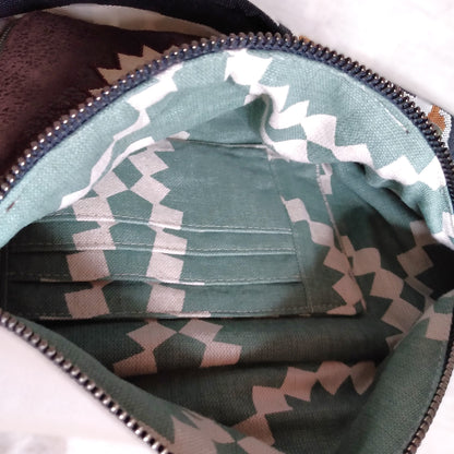 Intérieur du sac banane mango. On y voit une poche plaquée avec des compartiements à carte. Le tissu de doublure est de couleur verdé avec des motifs géométriques  en forme de soleil beige.