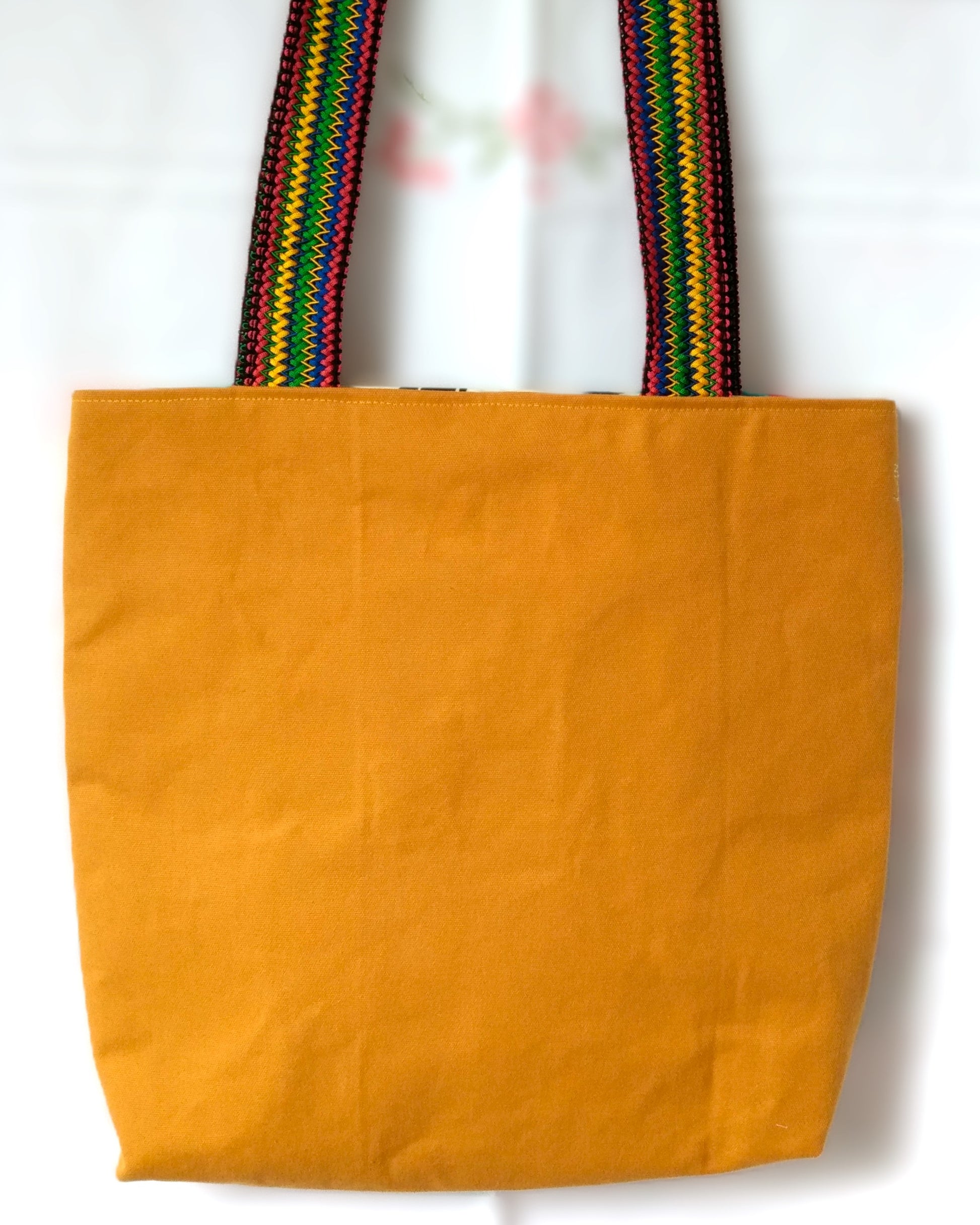Arrière du sac Ginger. Tissu uni jaune moutarde. Les anses sont multicolores.
