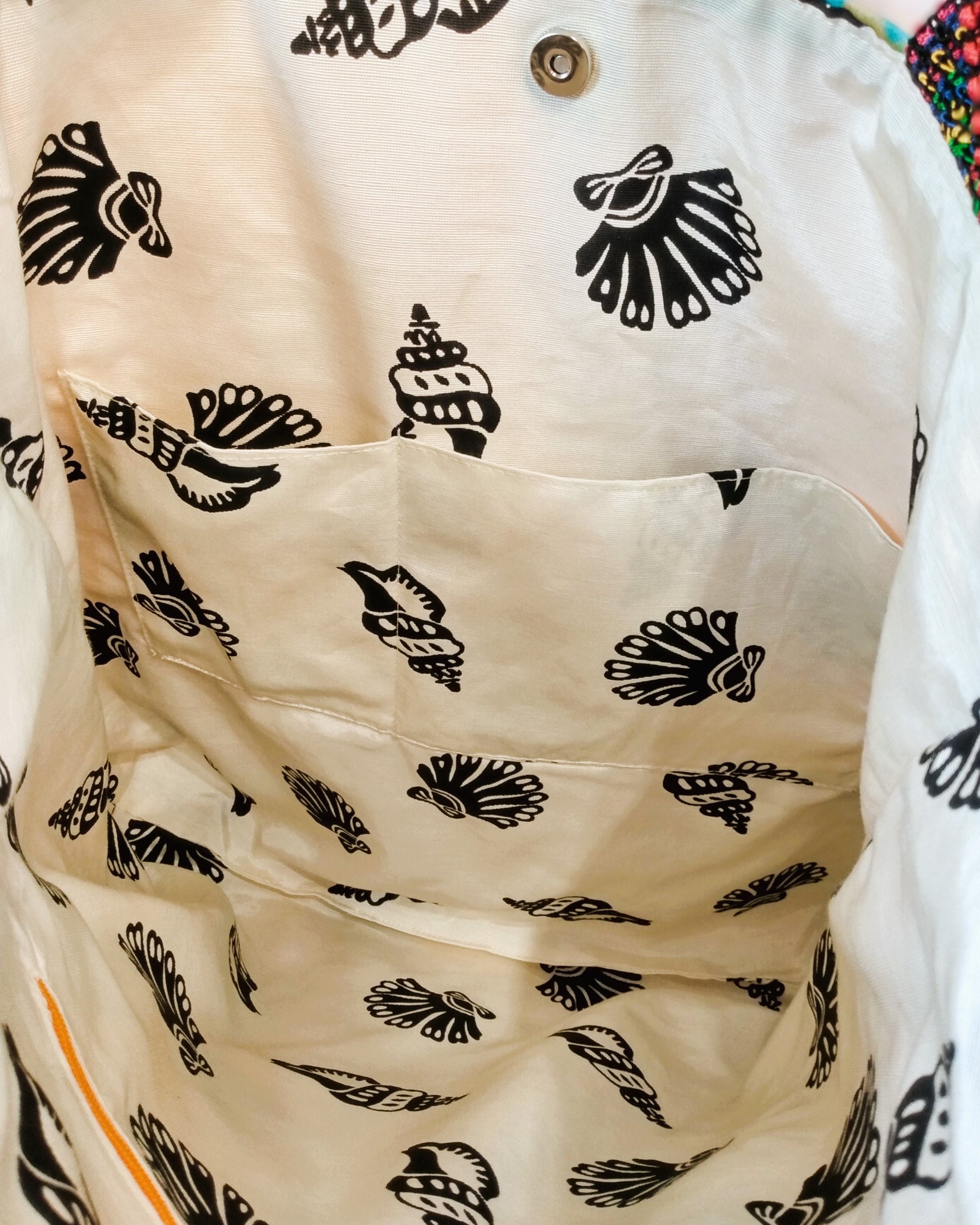 Intérieur du sac Ginger, autre vue. Le tissu de doublure est beige avec de gros coquillages noirs. On voit deux poches plaquées et un fermoir aimanté pour fermer le sac.