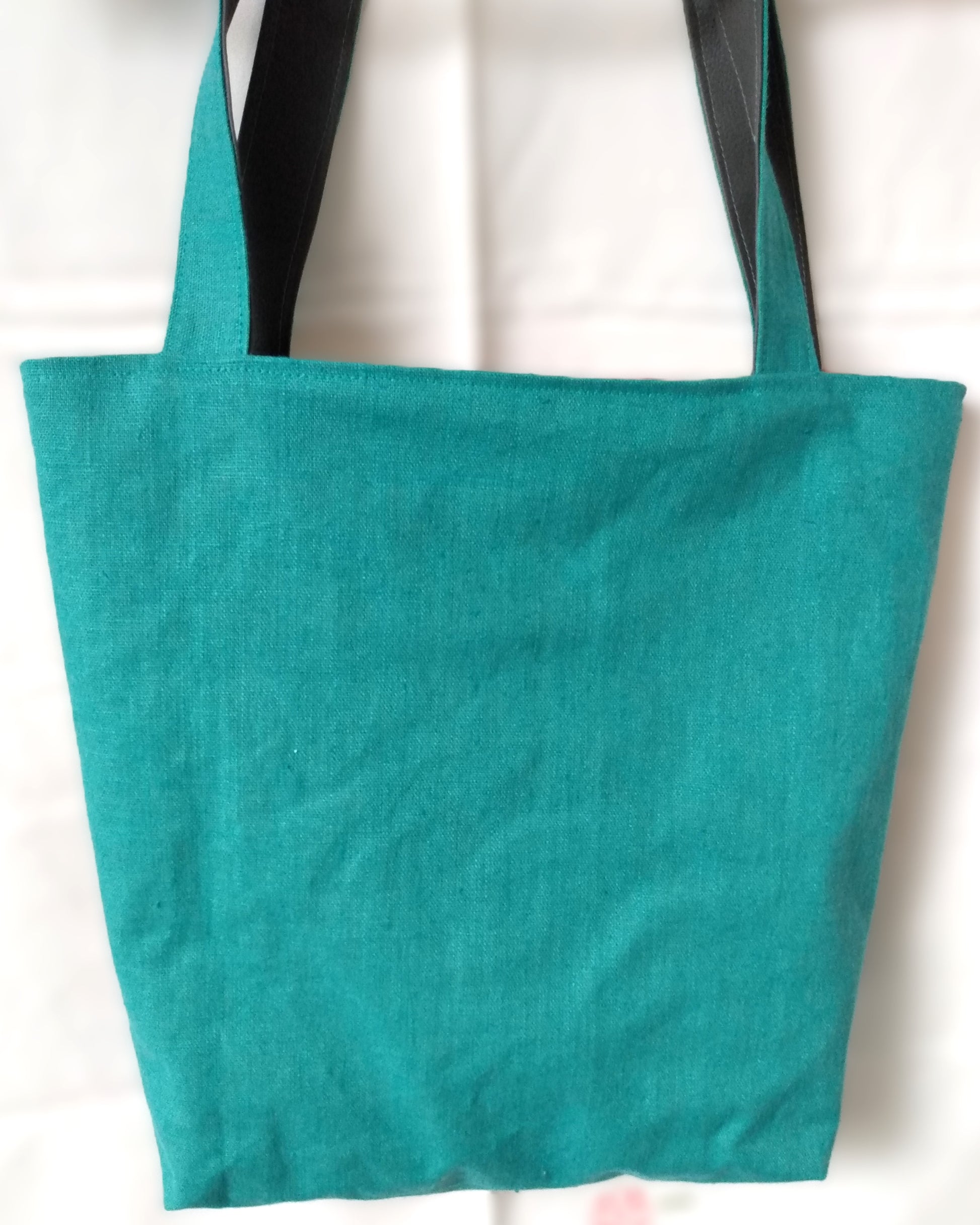 Arrière du sac Iris. En tissu uni bleu canard. Les anses sont dans le même tissu au recto et grises au verso.