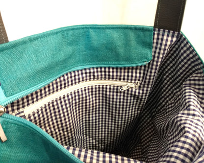 Intérieur du sac Iris. Le tissu doublure est à petits carreaux bleus et blancs. Une poche zippée (fermeture éclair blanche) est visible.