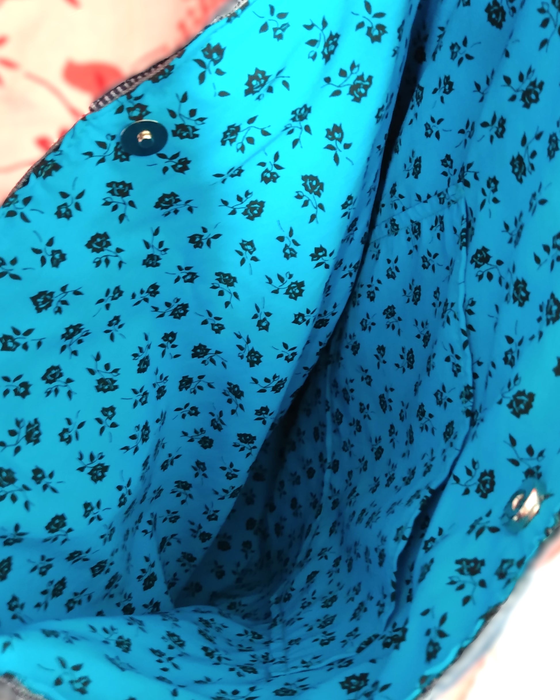 intérieur du sac Bleuet. Le sac se ferme avec un bouton fermoir magnétique métal. La doublure est en coton bleu ciel à petites roses noires. Une poche plaquée est présente.