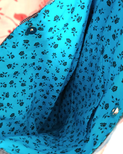 intérieur du sac Bleuet. Le sac se ferme avec un bouton fermoir magnétique métal. La doublure est en coton bleu ciel à petites roses noires. Une poche plaquée est présente.