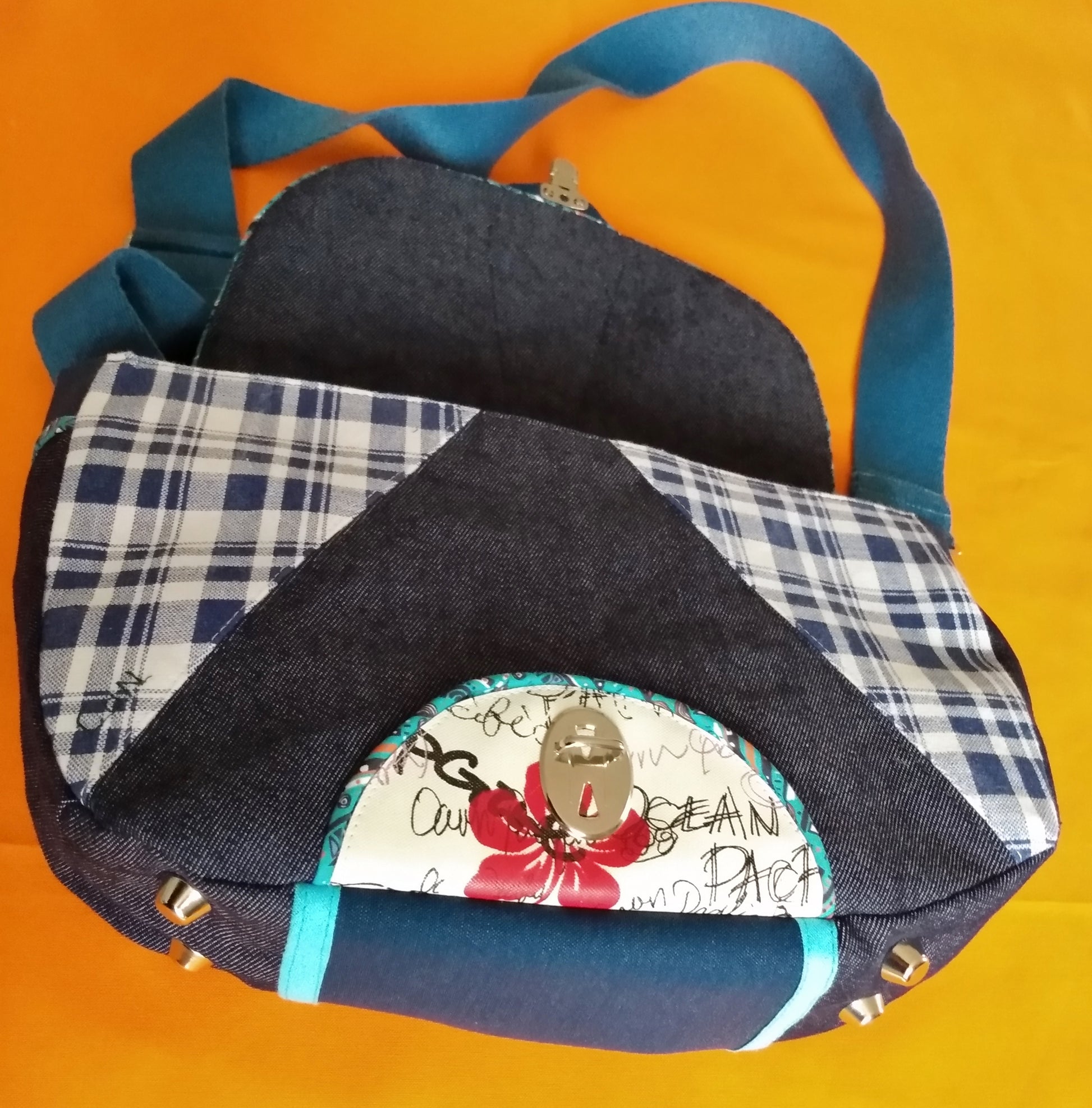 Avant du sac Vegas jean avec le rabat ouvert. On voit également le dessous du sac avec 4 pieds et au centre un empiècement simili cuir bleu foncé.